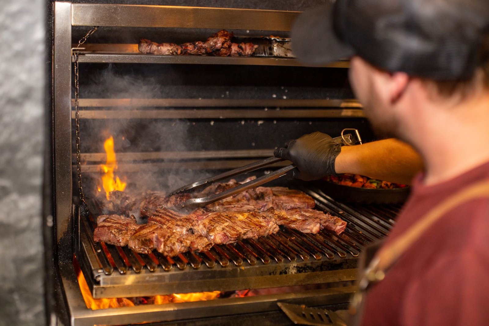 Chef grilling steaks over an open flame