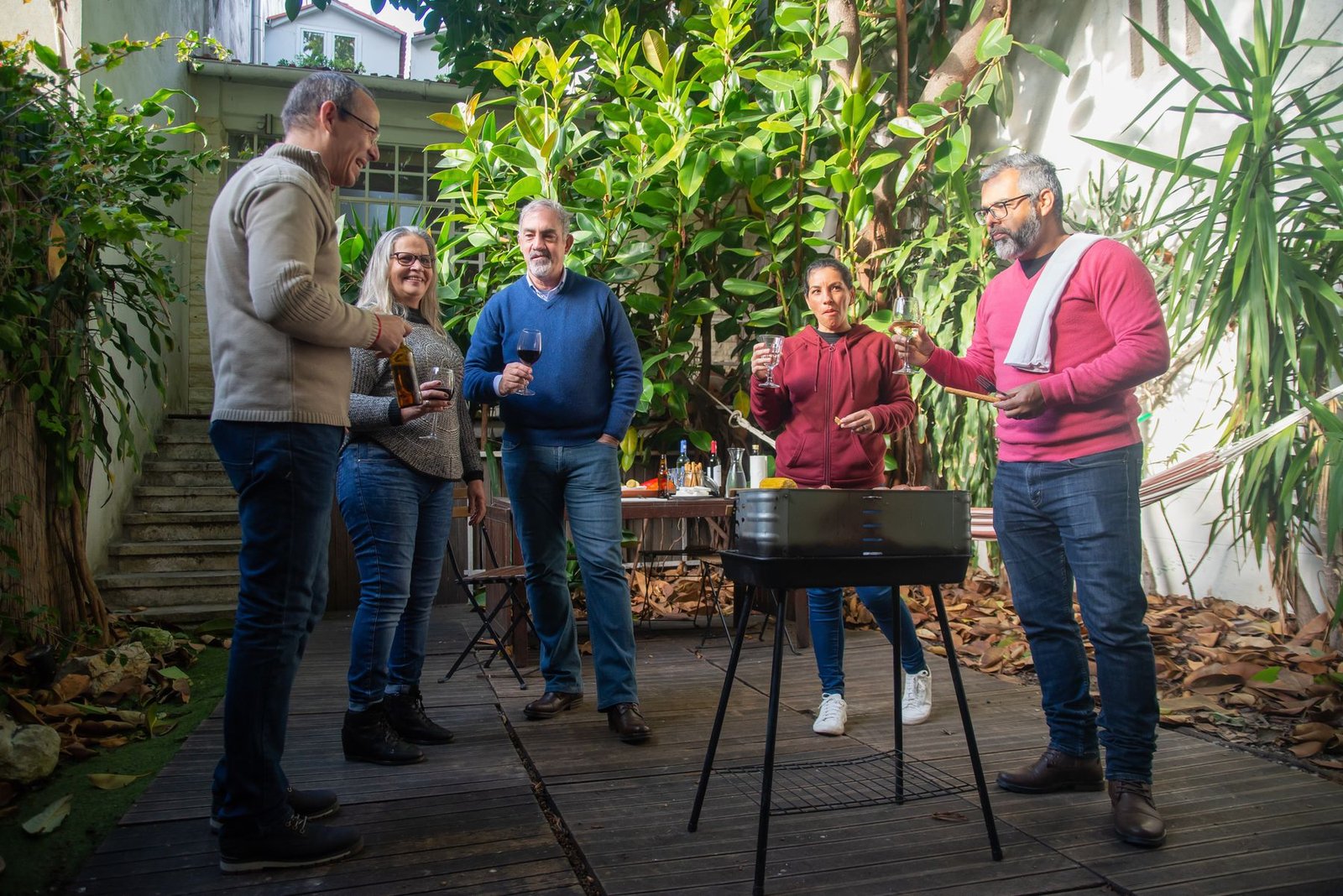 Friends gathering beside an outdoor barbecue grill